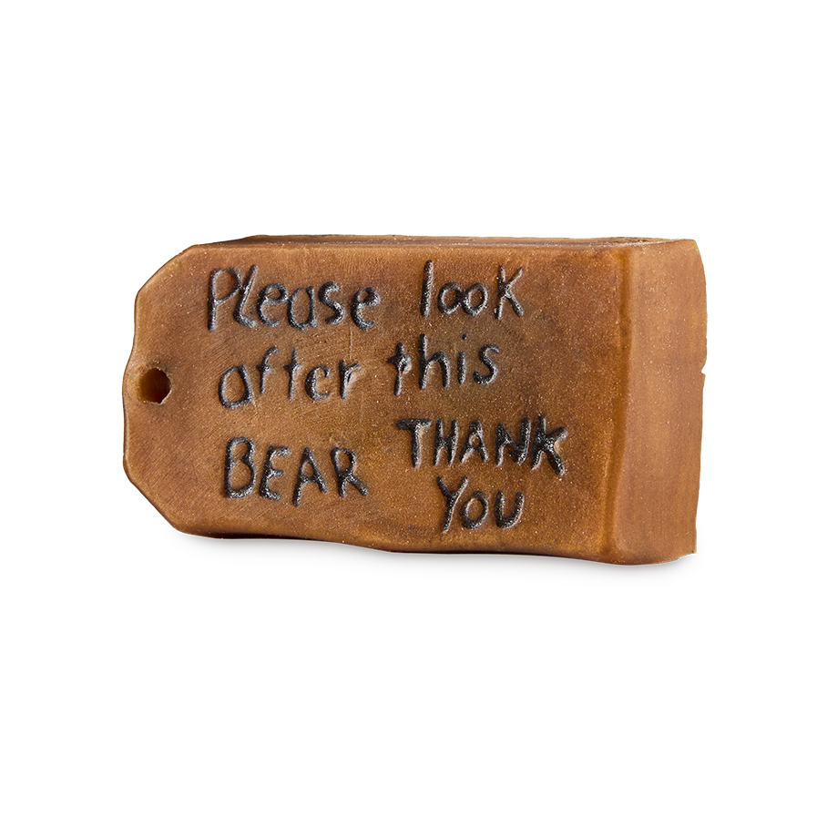 Please Look After This Bear. A brown, luggage-tag-shaped bar of soap inspired by Paddington Bear. The textured surface features the embossed message 'Please look after this bear, thank you' in handwritten-style script.