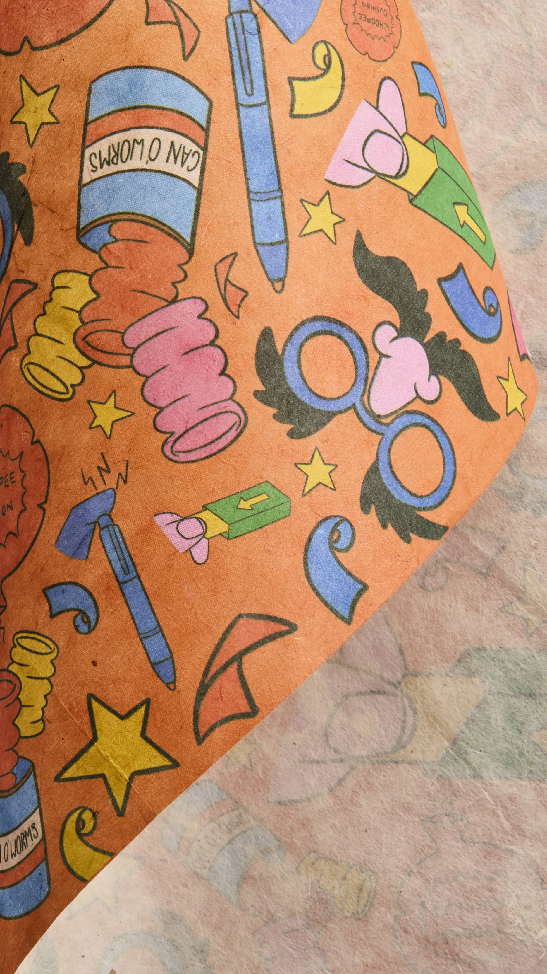 The image shows the thick, colourful sheet of orange Practical Joker lokta paper being gently rolled over itself to reveal its whitened, textured underside.
