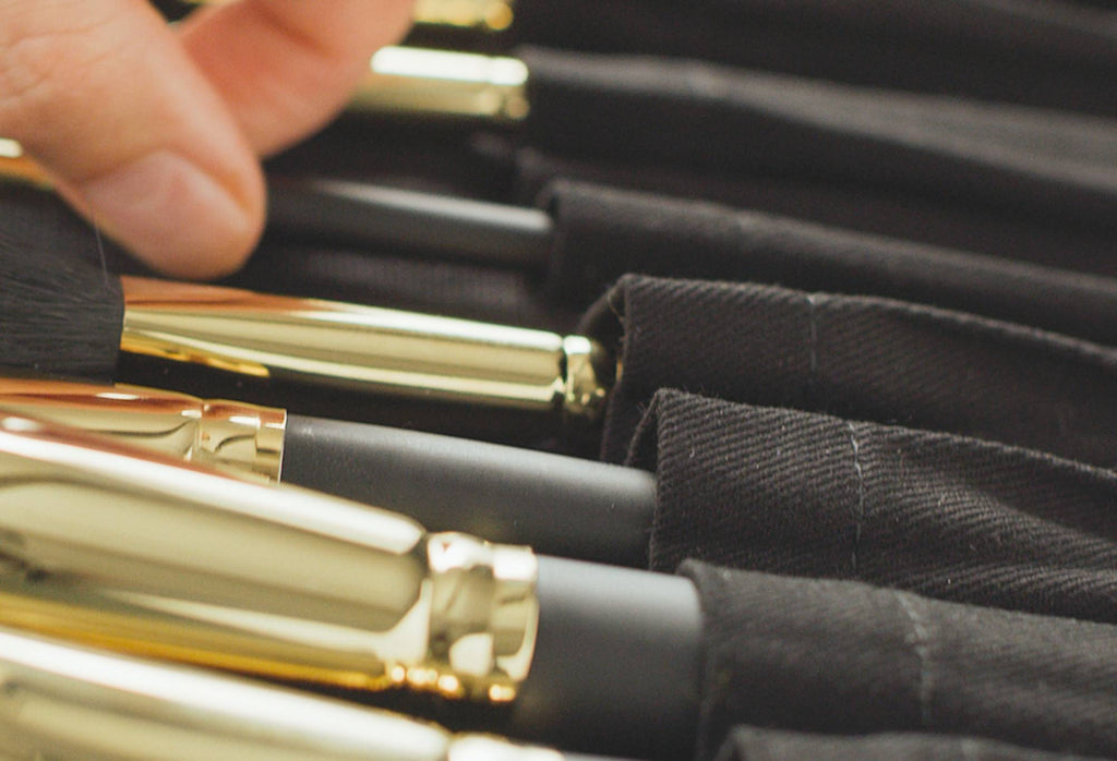 A close-up of Roll With It, a set of 13 handmade vegan make up brushes, wrapped up in a black, organic cotton storage wrap.