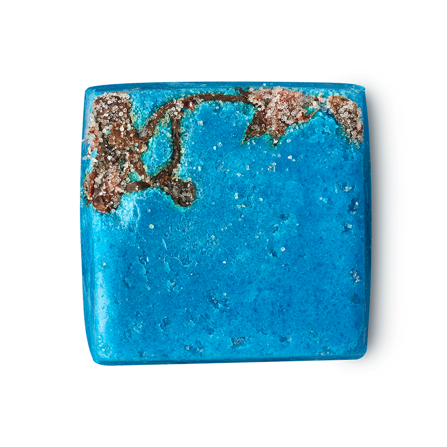 Rub Rub Rub. A cube-shaped, vibrant turquoise product. One corner features a rough brown patch with salt crystals. The blue surface is smooth with tiny flecks.
