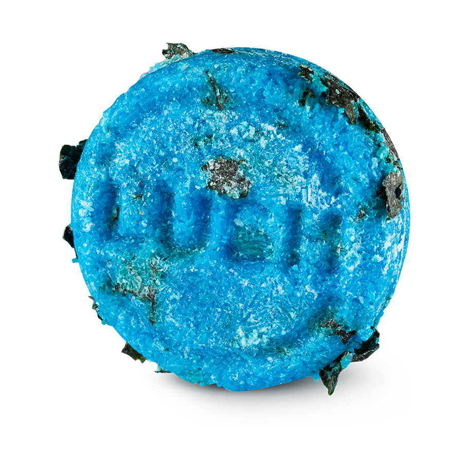 Seanik. A circular, bright blue Lush solid shampoo bar embossed with the word 'LUSH' in the centre. The highly textured bar is speckled with pieces of dark green seaweed.