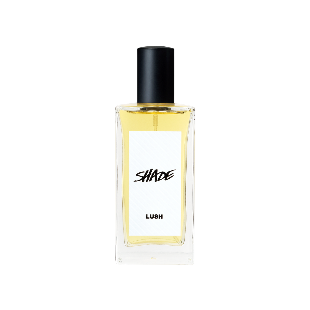A glass perfume bottle filled with pale yellow liquid. A white label reads 'Shade'.