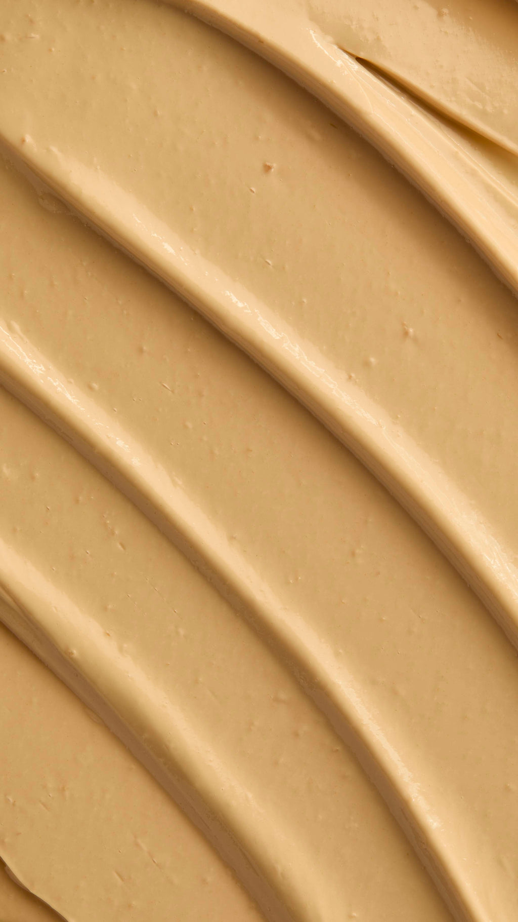 A macro texture shot showing the ridges of skin drink, beige cream spread in diagonal lines.