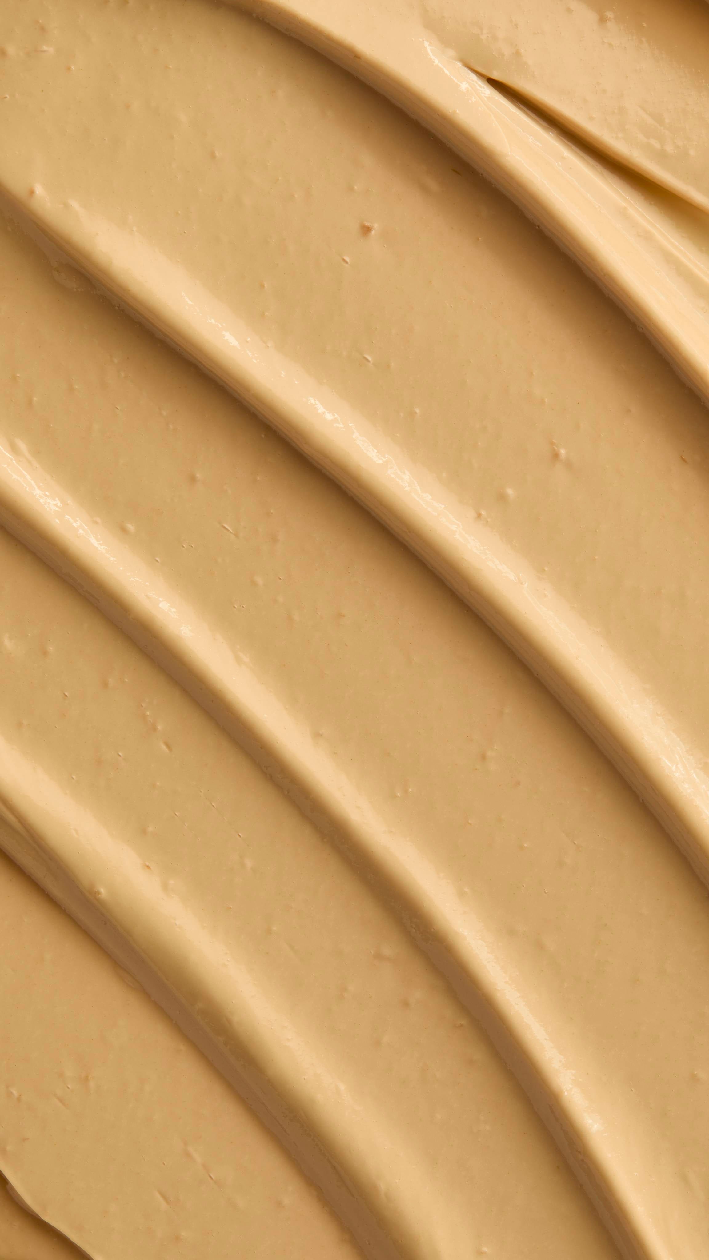 A macro texture shot showing the ridges of skin drink, beige cream spread in diagonal lines.