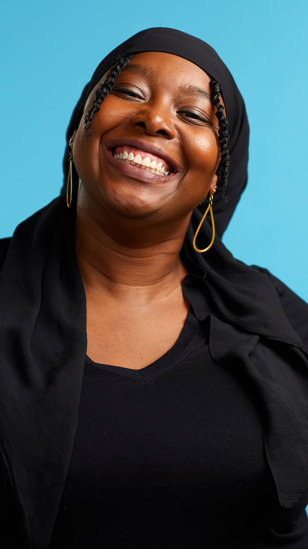 The image shows the model on a sky-blue background wearing a back top. They have just brushed their teeth with the Soother toothpaste and are smiling at the camera with gleaming, shiny, fresh teeth.
