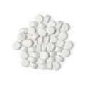 A pile of small, circular, white Sparkle toothpaste tabs shot from above.