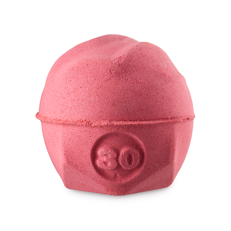 Sticky dates. A wavy, spherical bath bomb with a flat, geometric base. The product is a warm, caramel/rust colour and has the number "30" embossed on the side.