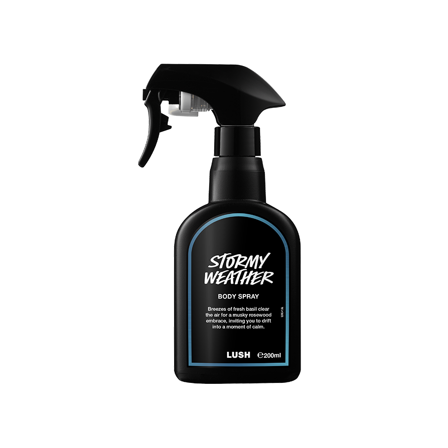 A recycled black plastic LUSH body spray bottle with a trigger nozzle stands upright with a deep blue rimmed label with white text that reads "Stormy Weather Body Spray".