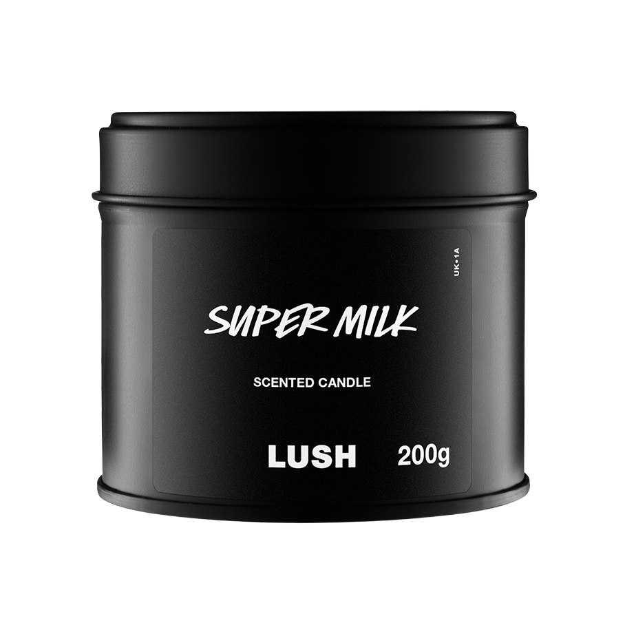 A black product shot of the Super Milk Scented Candle in a round, matte black tin with a fitted lid. The label features the product name in a white, handwritten-style font, with "SCENTED CANDLE" and "LUSH 200g" below it.