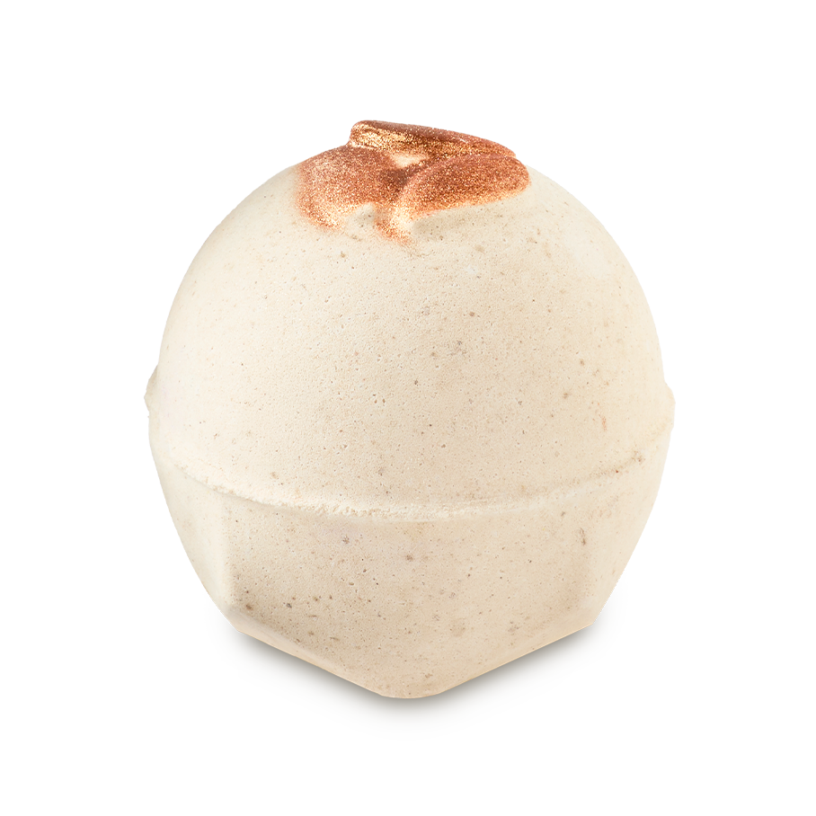 Super Milk. A spherical, off-white bath bomb with a speckled texture and flat, geometric base. The top features three embossed, decorative, shimmering bronze almonds.