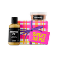 Sweet As Pie. A Lush gift set featuring a box wrapped in pink, orange, and white checked paper with a purple ribbon. It is presented with a bottle of Banoffee Pie shower gel and a pot of Crème Brûlée body scrub.
