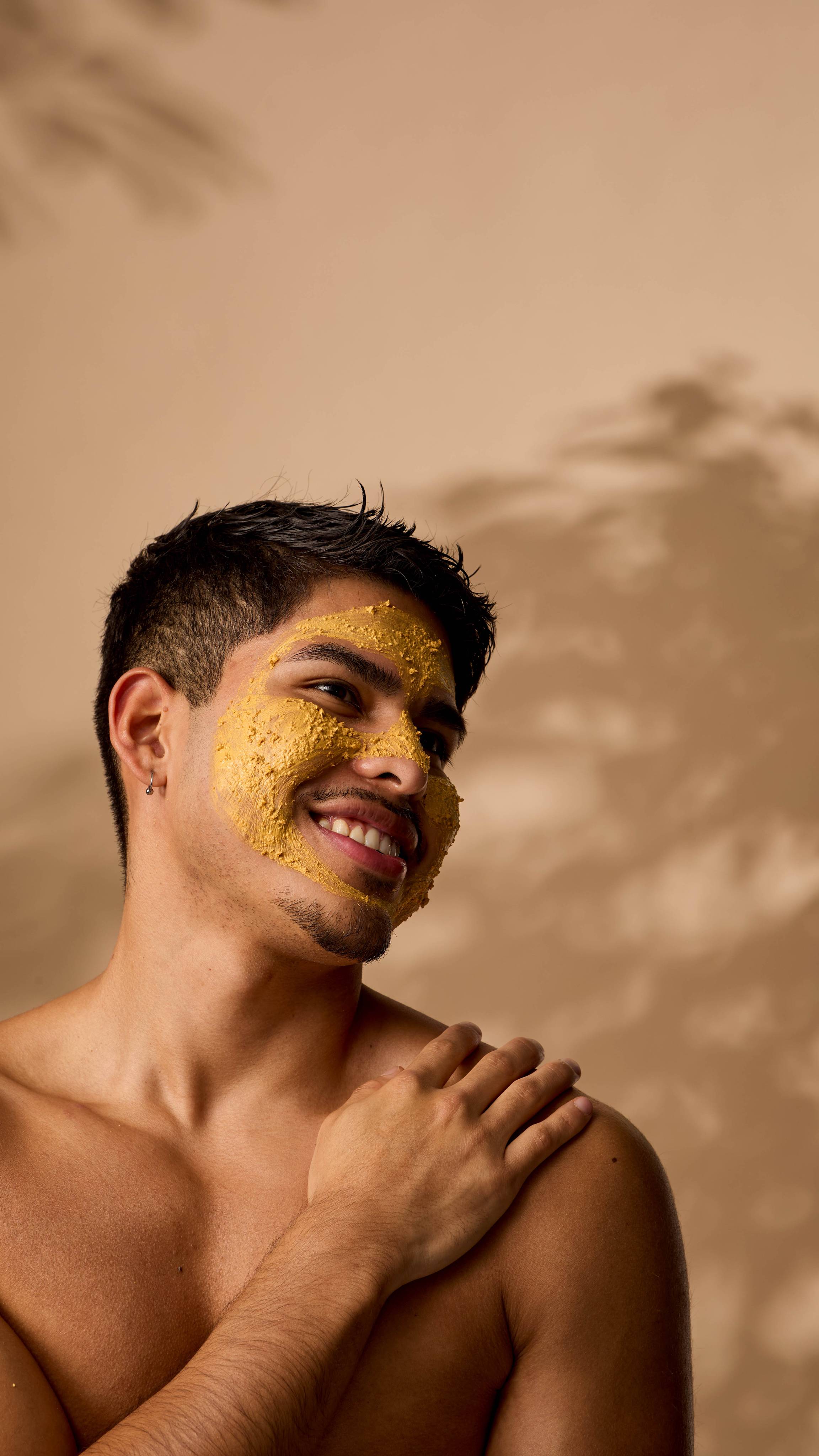 The image shows the model smiling into the distance as their skin is coated with the Turmeric face mask.