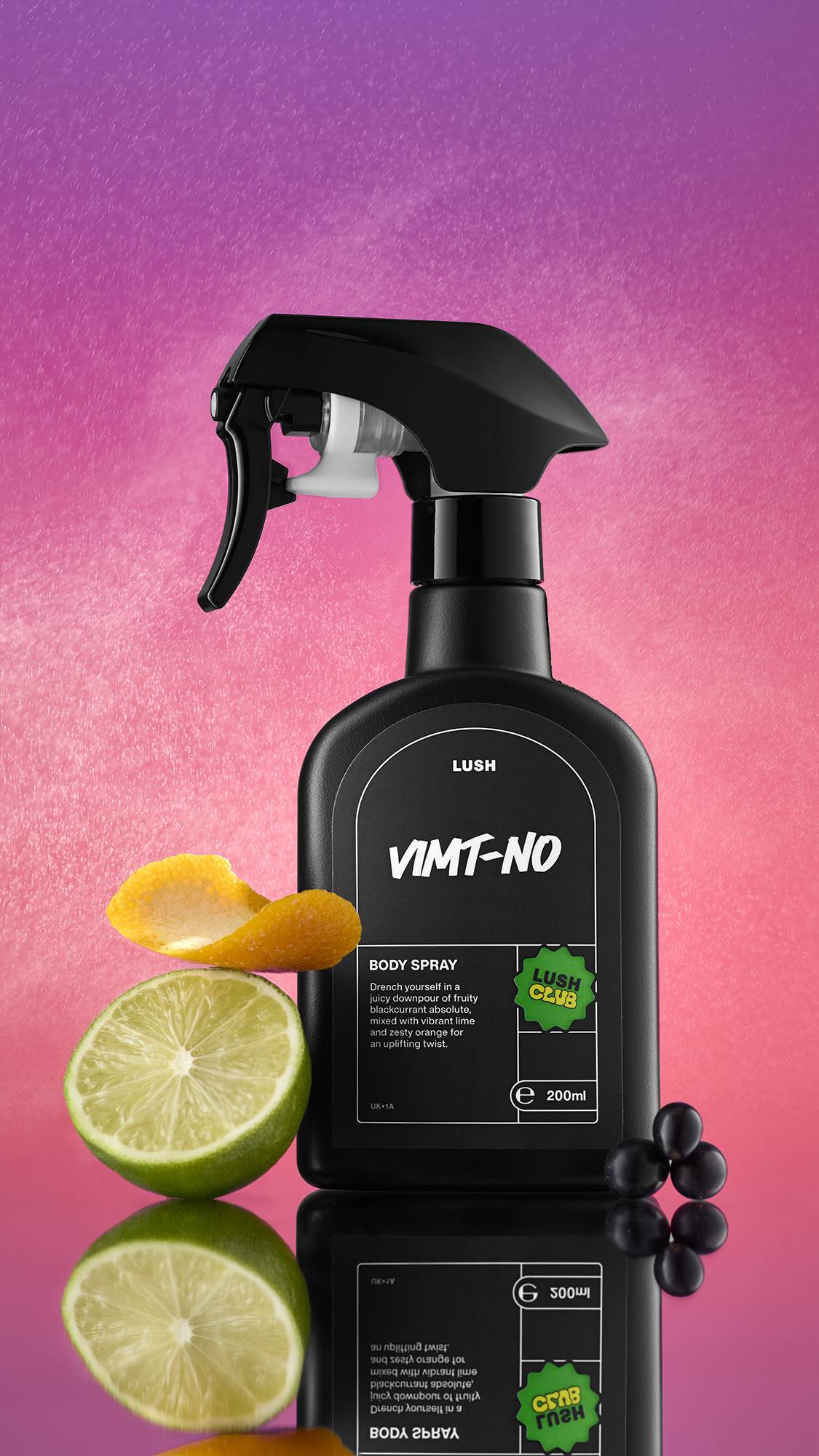 A black spray bottle of VIMT-NO Body Spray stands on a reflective surface against a vibrant pink and purple gradient background with fine water droplets visible. It is flanked by a lime half, a curl of orange peel, and a cluster of black berries.