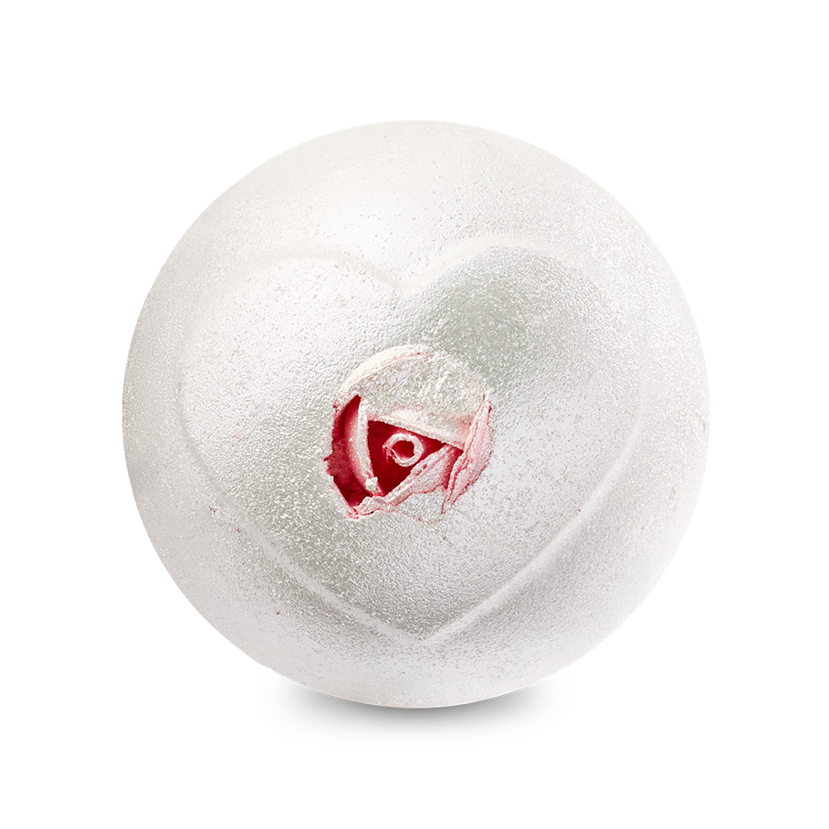 A top-down view of the Wedding bath bomb depicts a shimmering, pearlescent white sphere against a solid black background. An embossed heart shape on the surface reveals a realistic pink rosebud inside its center.